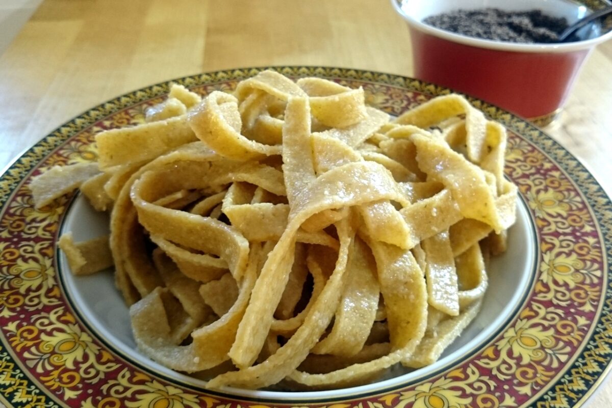 Selbstgemachte Kamut-Nudeln auf kunstvollem Teller, bereit zum Genießen.