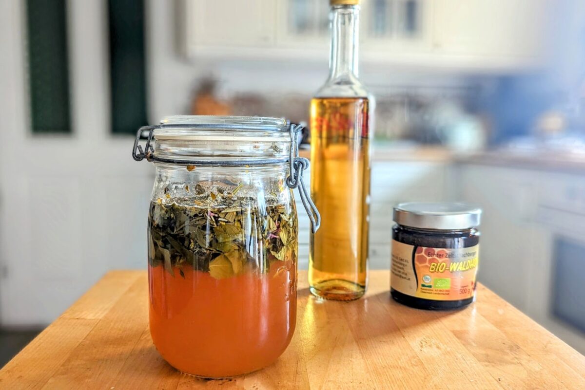 Ein Glas voller heilender Oxymel-Kräutermischung auf Holztisch.