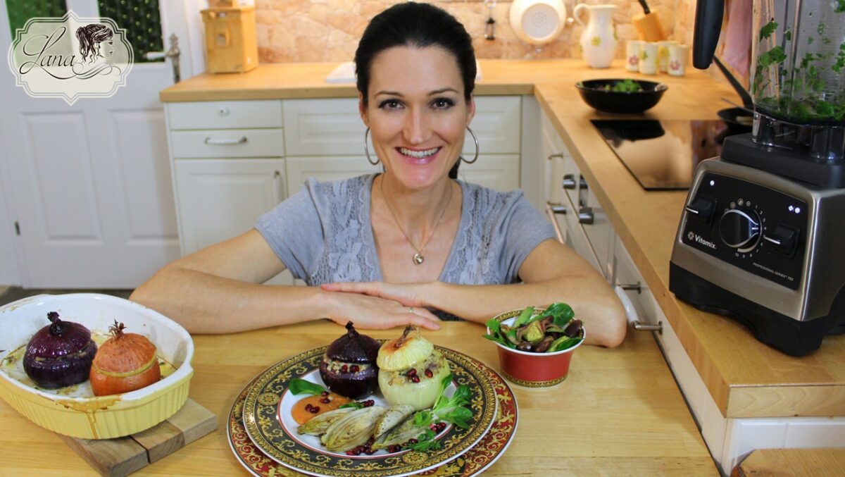 Eine lächelnde Person präsentiert gefüllte Zwiebeln mit Beilagen.